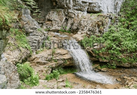 view of a small mountain river waterfall among large cobblestones from a cliff