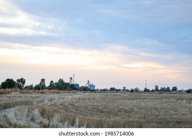 View of small town in regional Australia from a distance across bare paddock with grain silos visible