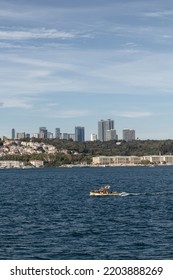 View Of Small, Wooden Fishing Boat On Bosphorus And European Side Of Istanbul. It Is A Sunny Summer Day.