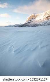 View Of Snow Capped Mountains In Sweden With Rocks In The Foreground, Bright Skies White Snow