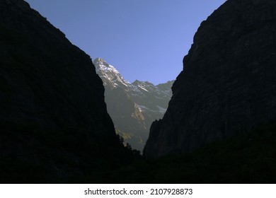 view of snow laden mountain through two rockfaces