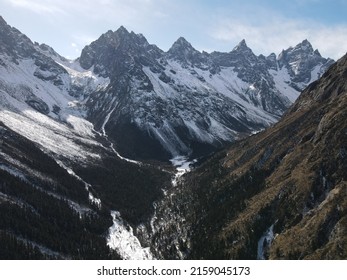 A View Of A Snowy Road Between Range Of Mountains Against A Light Blue Sky Rogers Pass, Canada