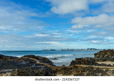 View south across the water from rocky beach at Currumbin to Coolangatta on the horizon. 