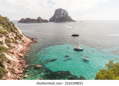 View from the southern edge of Cola d'Hort bay to transparent Mediterranean seawater with few yachts and 2 small rocky islands Es Vedra and Es Vedranell. Ibiza, Balearic Islands, Spain