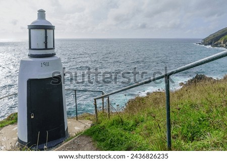 View of the Spy House Point Lighthouse (number marks the building year: 1911), in the fishing village Polperro, Cornwall, England, UK