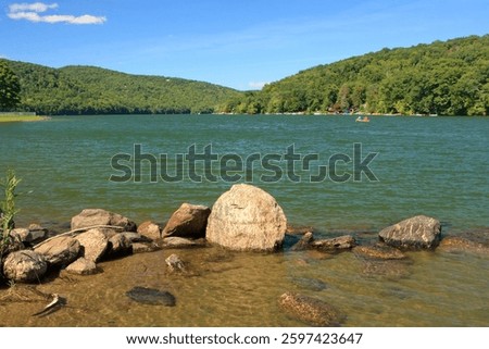 View of Squantz Pond with rocks in the foreground and mountains in the background.