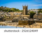 View of St. Ives, Cornwall, England, on nice summer day with shore, buildings and old parish church; blue sky in background 