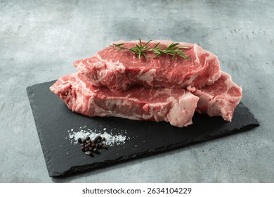 A view of a stack of choice New York steaks, on a slate board.