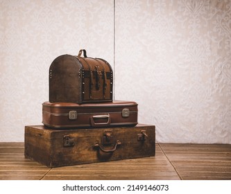 View of a stack of old classic suitcases on a wooden floor.