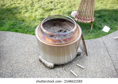 A view of a stainless steel fire pit, in a backyard setting.