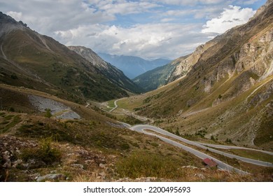 View of the Stelvio pass on the Swiss side in Alps with the many turns of it, incredible landscapes and a mountain glacial massif in the background