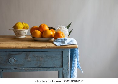 View of still life with lemons, oranges and grapefruits on rustic wooden table with checkered cloth and flowers, white background, horizontal with copy space - Powered by Shutterstock