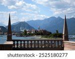 View from the stone building of a small Italian village with a pier, restaurant and bell tower against a blue sky background