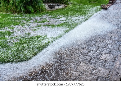 View At Stone Path And Green Garden With Hail Stones During Hailstorm From Sky With Sunlight