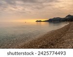 A view of the stone pebble beach and clear water at Letojanni on Sicily at sunsest
