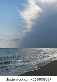 The view of storm clouds approaching the calm and waveless sea and beginning to block out the sun