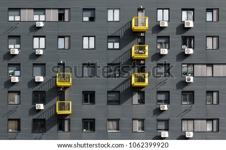 A view at a straight facade of a modern building with a dark grey facade and yellow balconies in Belgrade, Serbia