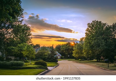 View Of Street In Suburban Midwestern Neighborhood In Summer; Sunset Sky In Background
