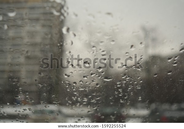 View of the street through the misted glass\
with drops of water. Day, cars,\
houses.