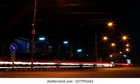 The View Of The Strip Of Light From The Car Headlights That Pass On The Road, Which Has A Lamp Installed To Illuminate The Side Of The Street At Night.