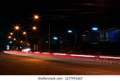 The View Of The Strip Of Light From The Car Headlights That Pass On The Road, Which Has A Lamp Installed To Illuminate The Side Of The Street At Night.