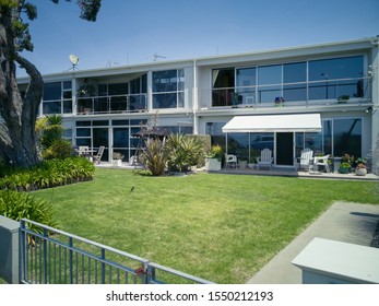 View Of A Suburban House Split Into Two Apartments With Green Grass In Front