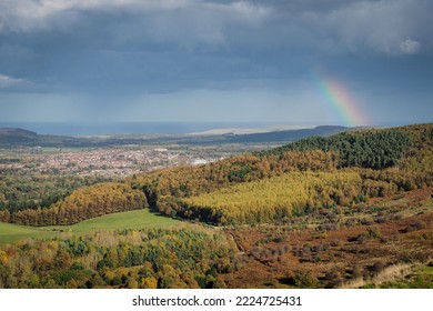 View from the summit of Roseberry Topping, Yorkshires Matterhorn, with a rainbow arcing over Guisborough under a moody sky, North York Moors National Park, UK - Shutterstock ID 2224725431