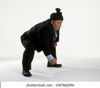 View Of A Sumo Wrestler In A Business Suit Squatting