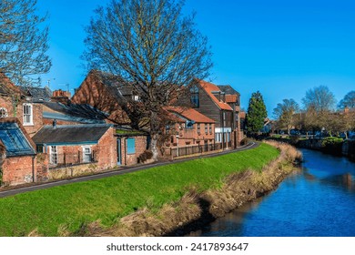 A view as the sun illuminates the side of the River Welland in the centre of Spalding, Lincolnshire on a bright sunny day