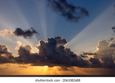 view of the sun rays shining from behind the clouds over a blue sky in the morning