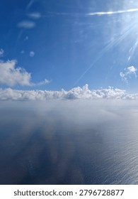 View of the sun shining through the clouds above the ocean