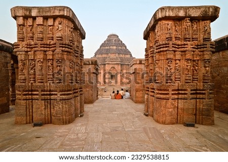 View of Sun temple between two intricately carved red sandstone pillars at Konark, India.