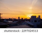 A view of the sunrise in Tokyo. An early morning in a residential area. There are silhouette of tall sky scrappers at far distance. 