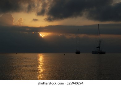 View of sunset in a cloudy sky over the sea with the silhouette of two boats, Italy