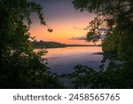 View of sunset on Missouri river framed by waterfront trees; sunlight reflect in water