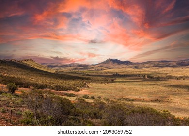 View at sunset over the vastness of the Australian Outback from Buckaringa North Camp Site over the Depot Flat to the South Flinders Ranges against sky with orange tinting veil clouds - Shutterstock ID 2093069752
