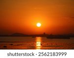 View of sunset over Wonsan harbor in North Korea showcasing the golden hues reflecting on water and silhouetted mountains