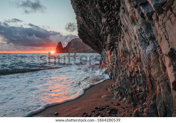 View of the sunset sea and the beach, the volcanic\
rock, sand and pebbles, volcanic basalt as in Iceland. Copy space.\
The concept of calmness, silence and unity with nature. Fiolent\
Sevastopol, Crimea