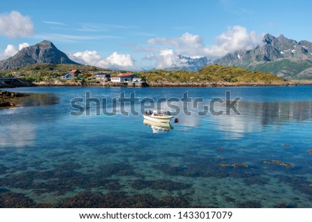 View from Svolvaer airport at coastline of Vestfjord with Lonely motor boat. Husvagen farm and mountain landscape of Austvagoya island are at background. Lofoten archipelago, Nordland, Northern Norway