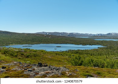 View of the Swedish highlands or fjeld world with mountain peaks and a small lake, on a beautiful summer day with blue sky and sunshine