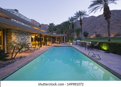 View of swimming pool and illuminated modern home exterior