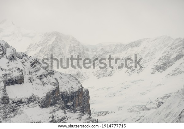 View of the Swiss mountains in winter. Eiger\
in clouds, Monoch and Jungfrau. Swiss alps in Jungfrauregion in\
Switzerland