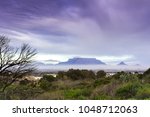 View of  Table Mountain covered in clouds at sunset with a dirt road curving through the landscape, Cape Town, South Africa