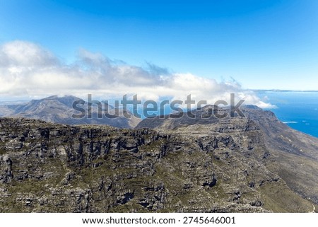 A view from Table Mountain of the mountaintops with clouds and the skyline in Cape Town, South Africa.