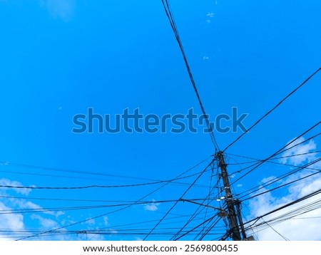 View of tangled messy electricity cable with white cloud blue sky background. Negative space
