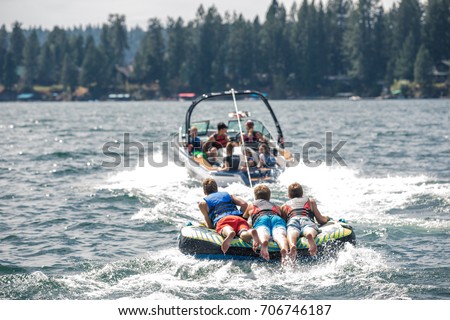View of the thee guys riding on a mat following a boat