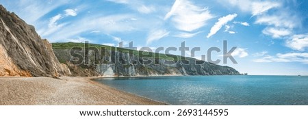 View of three large chalk stacks The Needles landmark in Isle of Wight rising out from steep coastal cliff edge with blue ocean sea background