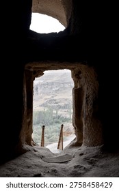 View through ancient cave window in Cappadocia Turkey looking over Goreme valley rock formations historical stone dwellings interior of cavern travel adventure tourism and archaeology concept