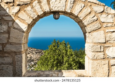 View through an arched window in a stone wall, revealing garden, mountains rise in the distance, stunning sea view stretches out to meet the horizon. Ideal for nature and travel-themed imagery - Powered by Shutterstock