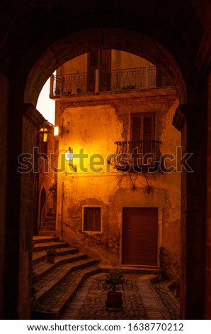 View through archway of beautiful building and street lamp in Sicily, Italy in early evening light. 
